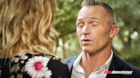Mona Wales in black floral dress chats intimately with Marcus London outdoors