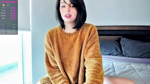 Cute Asian teen webcam babe in oversized yellow sweater smiling seductively on bed
