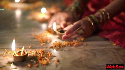 Desi woman in red sari lighting diyas with marigolds in festive homemade tease