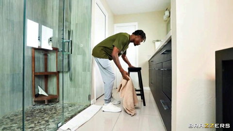 Fit black guy in sweatpants bending over picking up towel in steamy bathroom