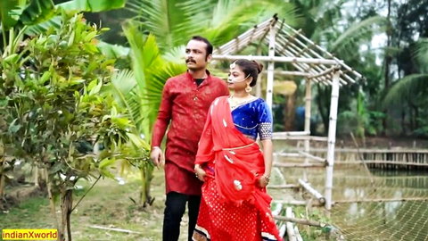 Indian couple in red traditional attire walking in lush outdoor setting from desi web series