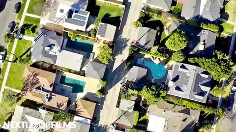 Aerial drone view of suburban neighborhood with turquoise backyard pools and modern homes
