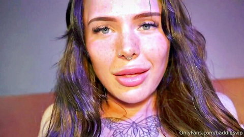 Aurora Del Ray close-up with purple hair, butterfly tattoo and cleavage