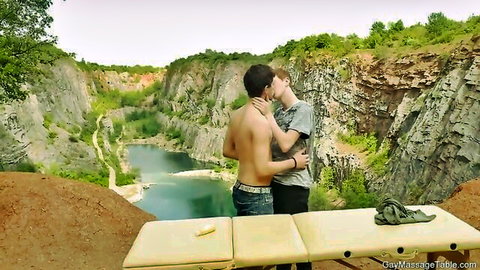 Two muscular men embracing passionately on massage table in scenic canyon