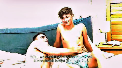 Two shirtless young brunettes sensually embrace and smile on bed in gay teen video