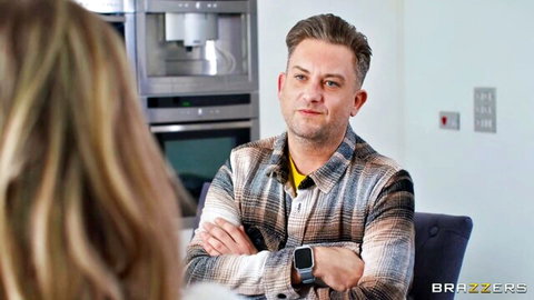 Blonde woman facing handsome man in plaid shirt arms crossed in modern kitchen