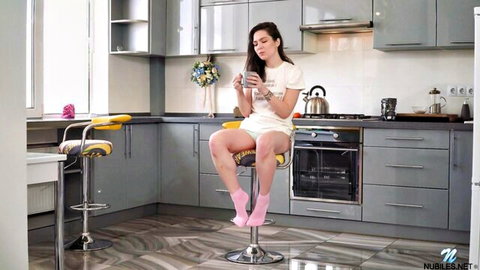 Monica Melody in white panties and pink socks, sitting legs apart on stool