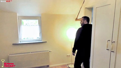Man in black hoodie standing in bedroom looking toward open closet door