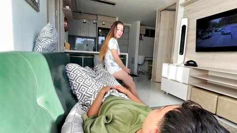 Blonde teen in short white dress straddles stepdad's lap on couch teasing him