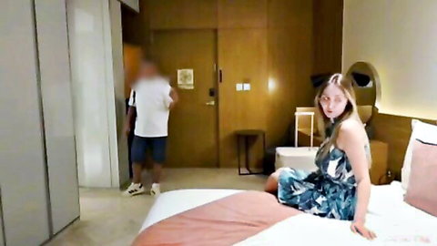 Blonde MILF in floral dress sits on bed with young man entering room