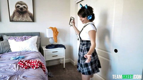 Cute teen neko girl in short plaid skirt and crop top holds phone posing in bedroom