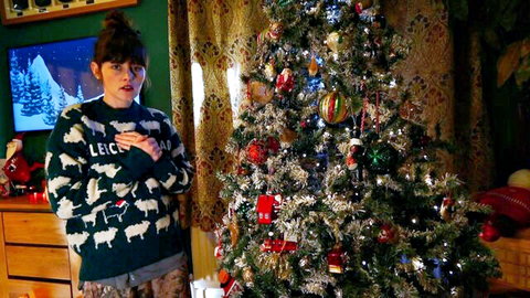Naughty brunette MILF in festive sheep sweater stands by twinkling Christmas tree