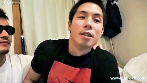 Two sexy Asian men in t-shirts embracing on bed, intimate gay moment