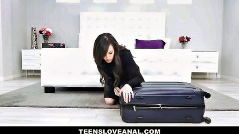 Brunette babe in tight black dress kneeling over suitcase teasing ass in bedroom