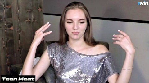 Vika Lita posing seductively in silver sequin dress, long brunette hair