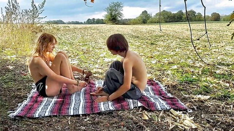 Topless ginger teen with guy on picnic blanket in outdoor field