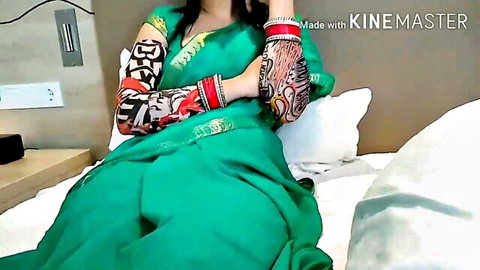 Tattooed Indian bride in sexy green saree lounging seductively on bed with bridal bangles