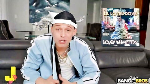 Clothed man in blue tracksuit and chef hat posing surprised on Bang Bros couch