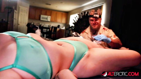 Tattooed pierced woman in sheer green lingerie during erotic tattoo session, Alterotic