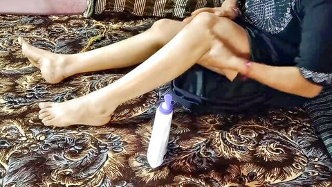 South Indian woman spreads legs wide barefoot on bed teasing with white bottle near pussy
