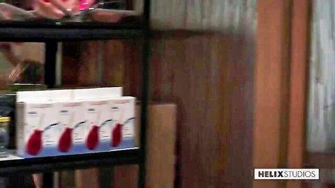 Hand grabbing pink lube bottle from Helix Studios shelf display in gay porn prep scene