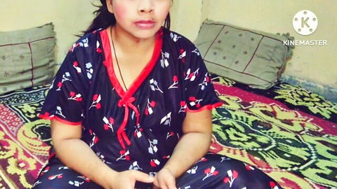Seductive Indian woman in revealing black floral nightie sitting on bed with cleavage tease