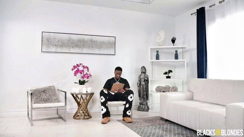 Handsome black BBC bull sits confidently in luxurious modern room before fucking blondes