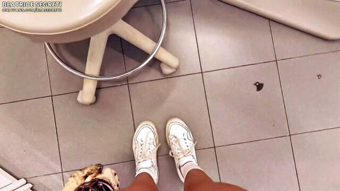 POV closeup of sexy tan legs in white sneakers standing in tiled medical office floor