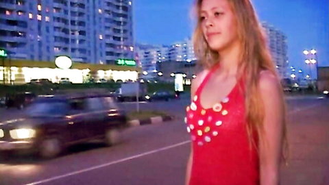 Blonde woman in sexy red beaded dress walking on urban street at night