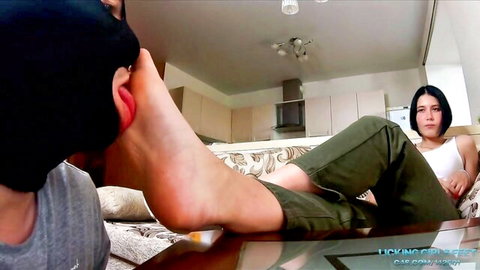 Brunette woman dominates man licking her bare foot soles in foot worship fetish
