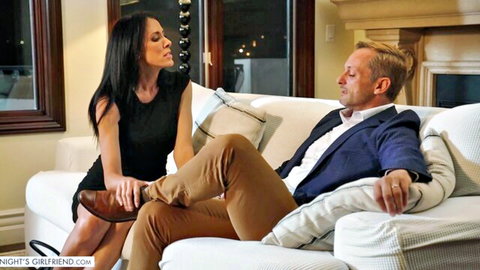 Brunette girlfriend in tight black dress flirts intimately with man on couch