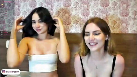 Two busty smiling babes in skimpy tops tease deep cleavage on cam with hands in hair