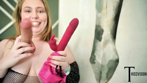 Smiling BBW blonde in black lingerie holding large dildos and vibrator