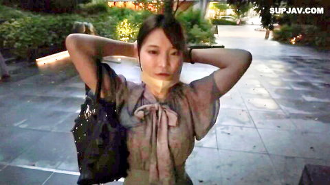Gagged Asian woman posing outdoors in blouse with hands behind head