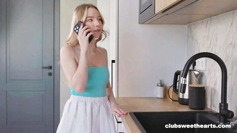 Blonde model Mirka Grace in cyan tank top and white skirt on phone