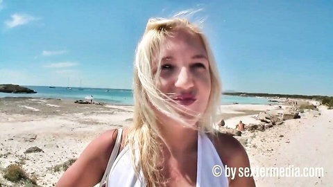 Blonde babe smiling on sunny beach in white tube dress showing deep cleavage