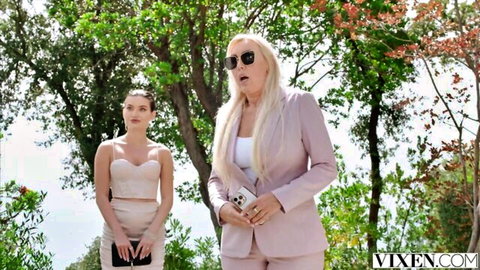 Sexy blonde MILF in pink suit with sunglasses and brunette babe in tight mini skirt posing outdoors by sea