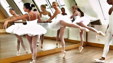 Group of sexy ballerinas in tight white leotards and tutus stretching legs high in mirror dance studio