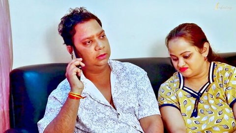 Indian MILF wife in yellow top gazes at shirtless stranger man talking on phone on couch