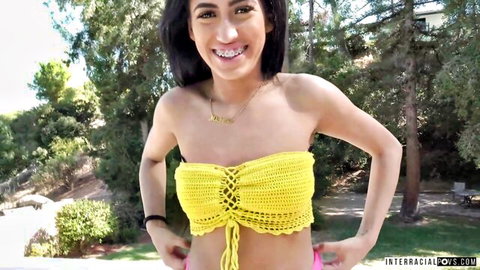 Smiling Arab brunette coed in skimpy yellow crochet bikini top posing outdoors teasing
