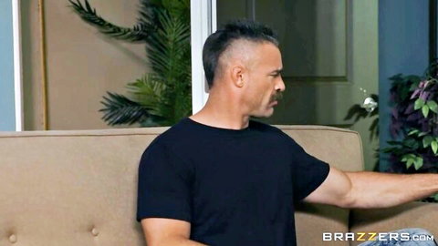 Muscular man in black t-shirt gesturing on couch in living room