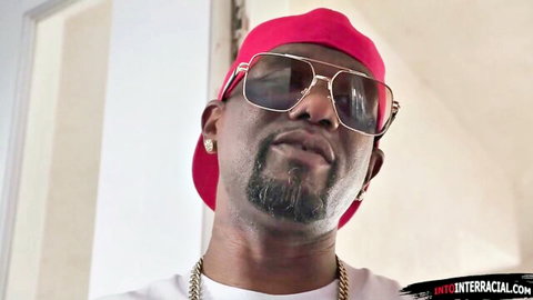 Sexy black stud with BBC smirking in red hat and gold shades for interracial action