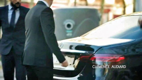 Clemence Audiard with suited men by luxury Mercedes car