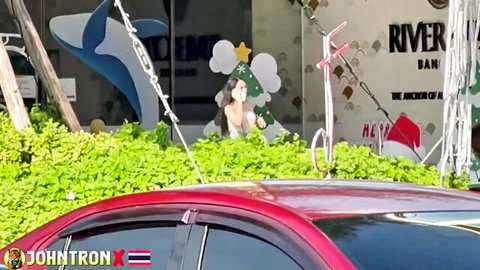 Nut 1 in white dress poses outdoors by red car, Christmas decor
