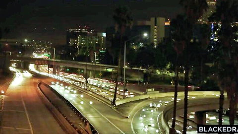Nighttime aerial view of Los Angeles freeways with traffic, palm trees and city lights
