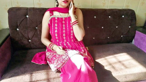 Sexy Indian woman in pink salwar kameez sitting on couch talking naughty on phone
