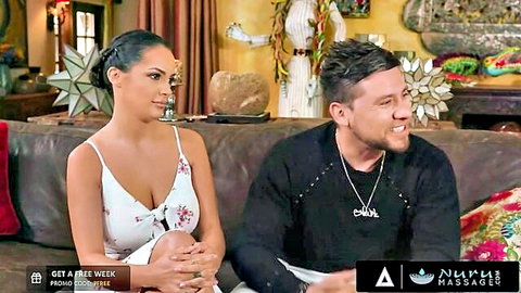 Curvy brunette with big natural tits in low-cut floral dress smiles at handsome man on couch