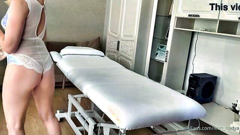 Blonde babe in sheer white lace bodysuit teasing round ass in massage room