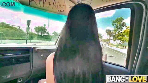 Alex Coal viewed from behind in bus, long black hair, bare shoulders