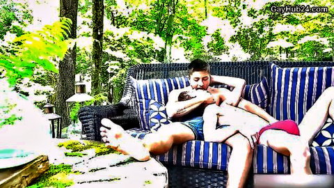 Muscular gay hunks passionately neck kissing shirtless on outdoor couch with huge cock bulge in red speedo